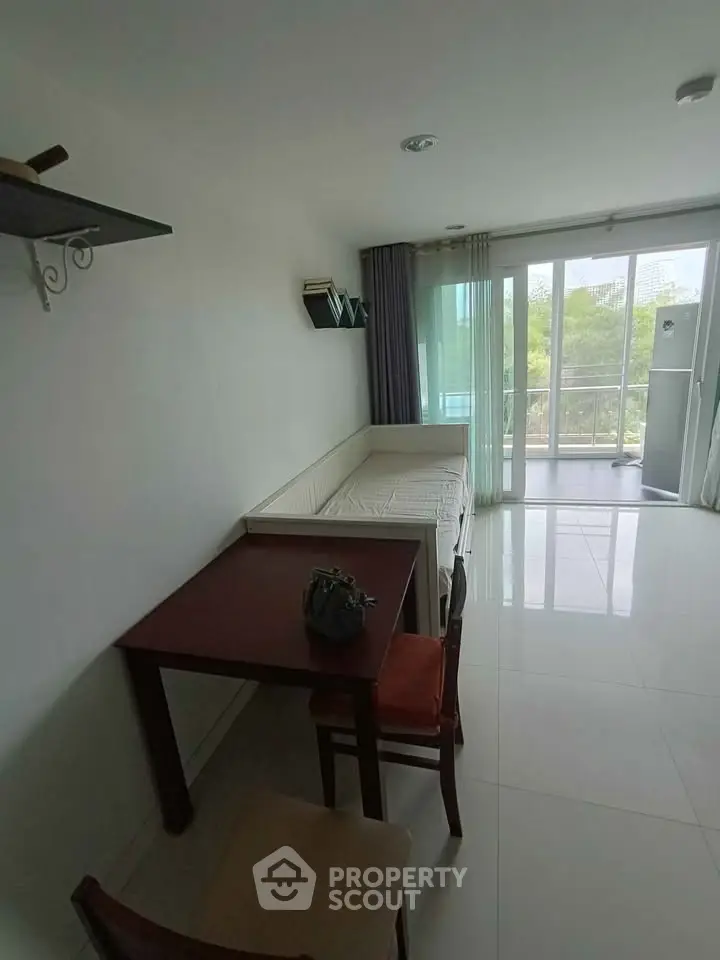 Bright living room with modern furniture and large windows leading to a balcony.