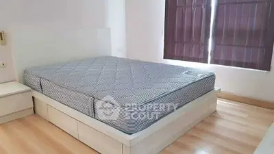 Spacious bedroom with modern bed frame and natural light from window.