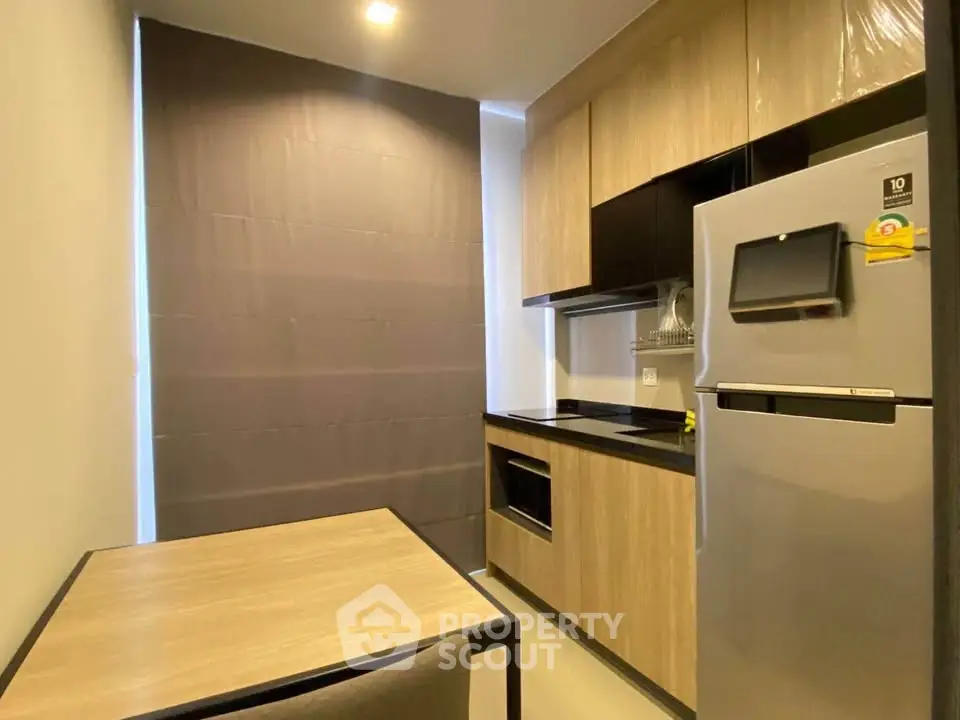Modern kitchen with sleek cabinetry and stainless steel fridge in a compact layout.