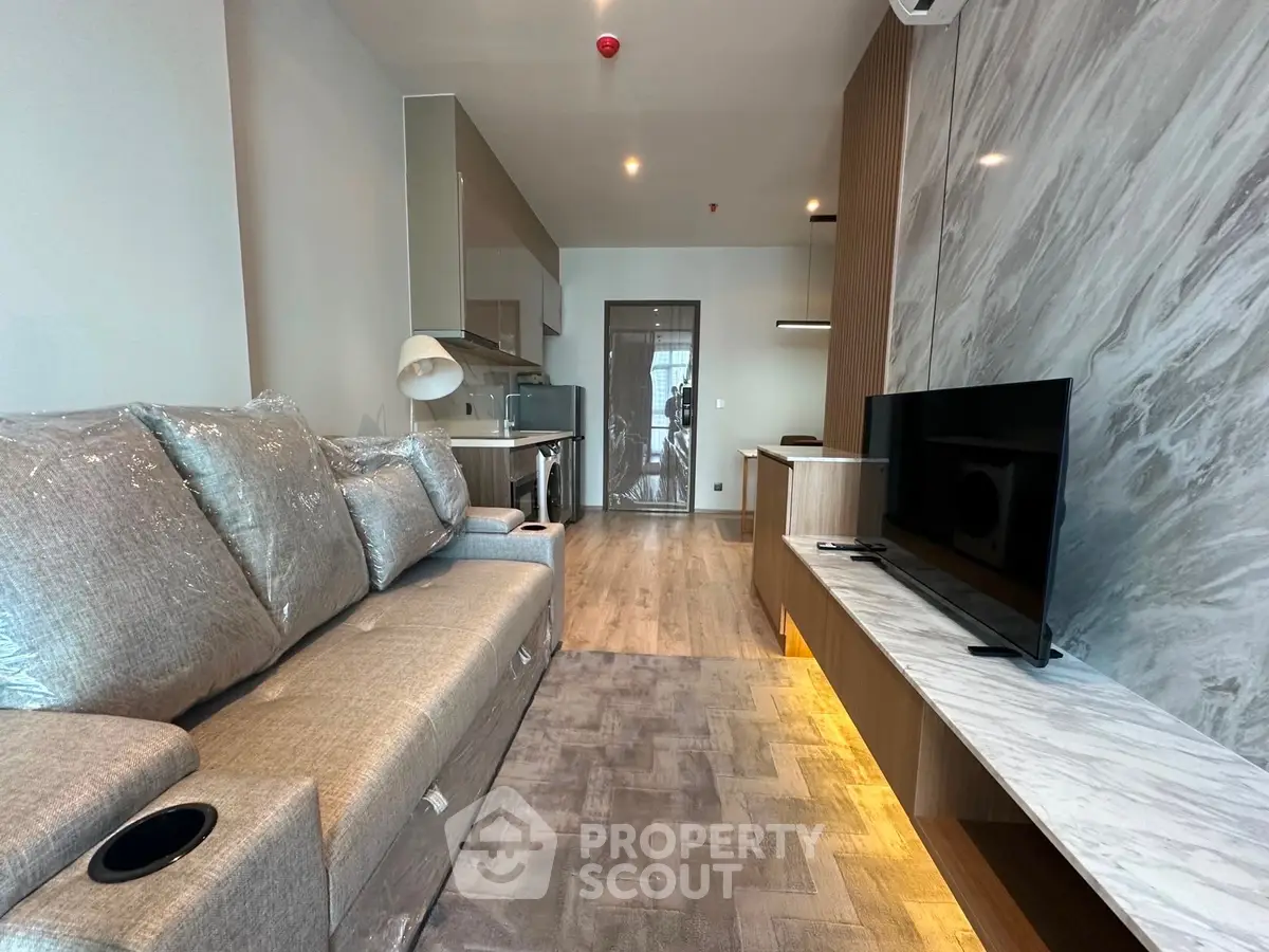 Modern living room with stylish decor and large TV, featuring a comfortable sofa and elegant lighting.