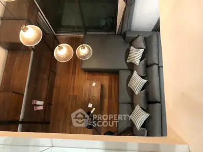 Modern living room with stylish gray sofa and wooden flooring, viewed from above.