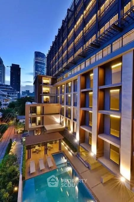 Luxurious modern apartment building with illuminated pool and stunning city view.