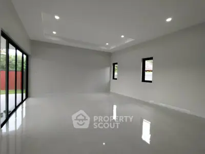Spacious modern living room with large windows and sleek tile flooring.