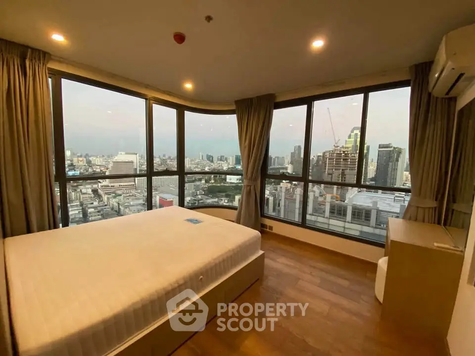 Stunning corner bedroom with panoramic city views and modern furnishings.
