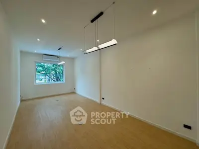Spacious empty room with large window and modern lighting, perfect for customization.
