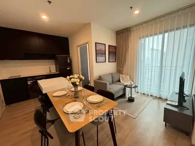 Modern open-plan living room with dining area and balcony access in stylish apartment.