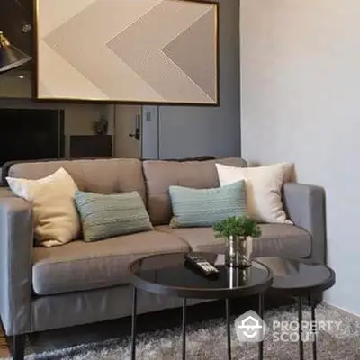 Chic modern living room with plush grey sofa, stylish geometric wall art, and elegant nesting coffee tables, perfect for urban living.