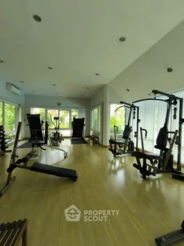 Spacious gym with modern equipment and large windows for natural light.