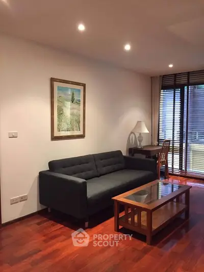 Elegant living room with modern sofa, wooden flooring, and natural light from large windows.