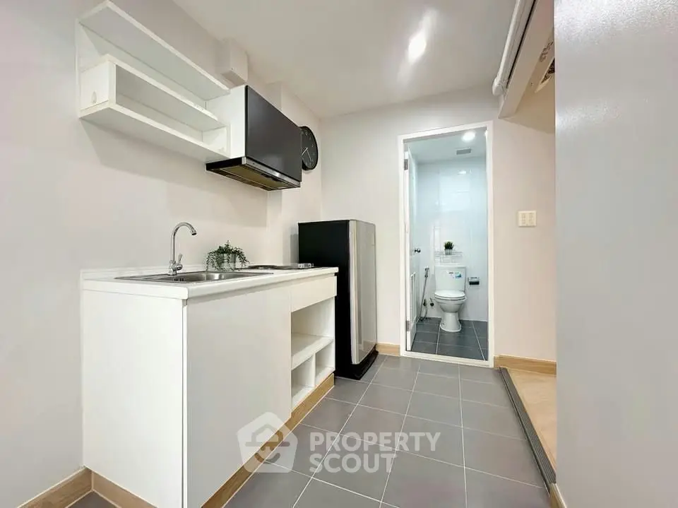 Modern compact kitchen with sleek design and adjacent bathroom in a cozy apartment.