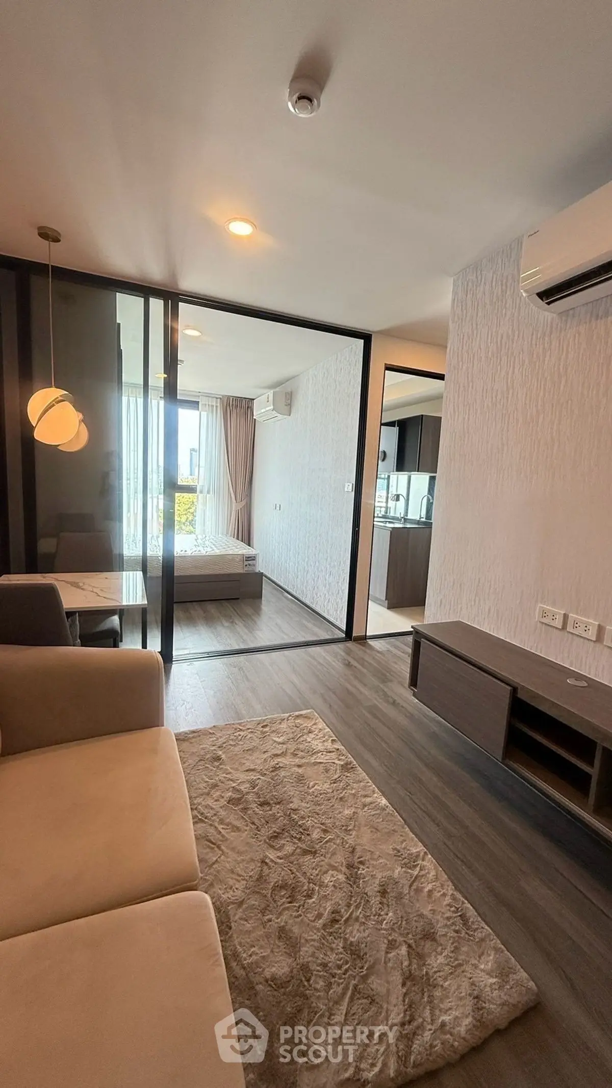 Modern apartment interior with open living room and bedroom, featuring stylish decor and natural light.