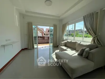Bright living room with large windows and cozy sofa, offering a view of suburban houses and a fenced yard.