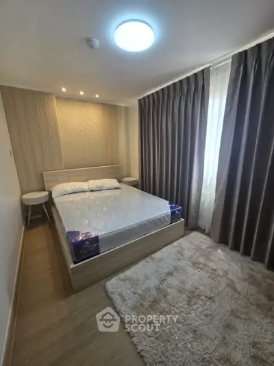 Cozy bedroom with modern decor, plush rug, and ample natural light from large window.