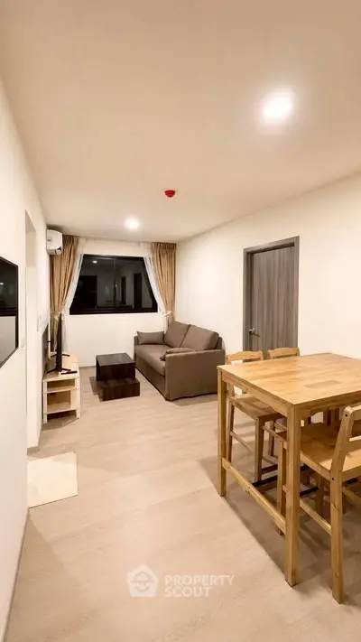 Spacious modern living room with wooden dining set and cozy sofa, perfect for relaxation and entertainment.