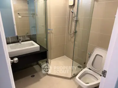 Modern bathroom with glass shower and sleek fixtures in contemporary home.