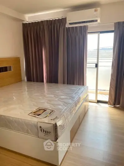 Modern bedroom with large window and air conditioning, featuring a new mattress and stylish curtains.