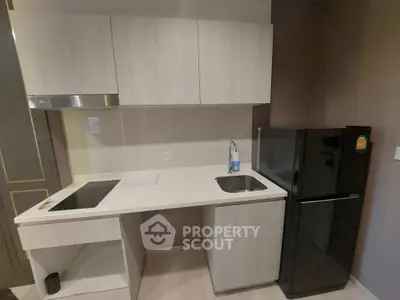 Modern compact kitchen with sleek cabinetry and black fridge