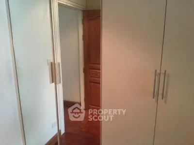 Spacious bedroom with mirrored wardrobe and wooden flooring