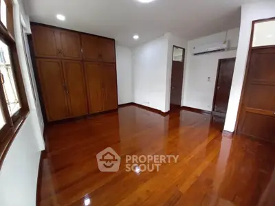 Spacious bedroom with polished wooden floors and built-in wardrobe