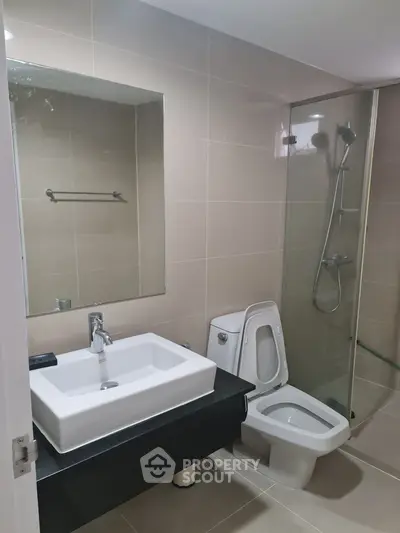Modern bathroom with sleek fixtures and glass shower enclosure in contemporary apartment.