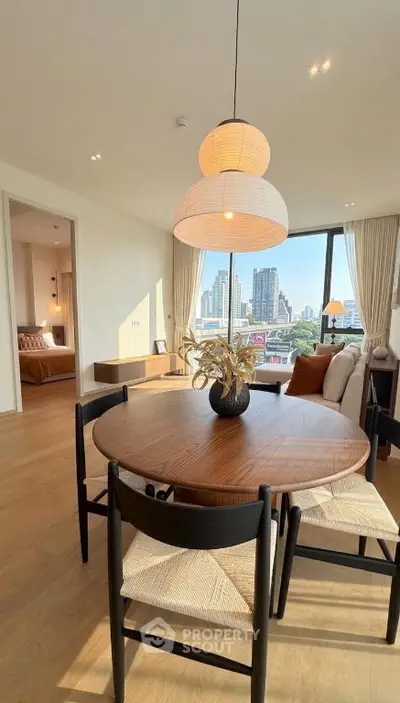 Modern dining area with city view, wooden table, and stylish lighting in a high-rise apartment.