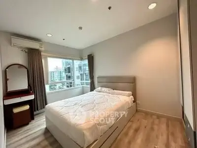 Spacious bedroom with modern decor and large window offering city views.