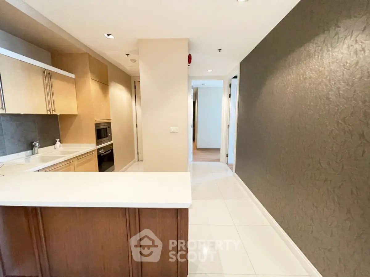 Spacious modern kitchen with sleek countertops and ample storage in a contemporary apartment.