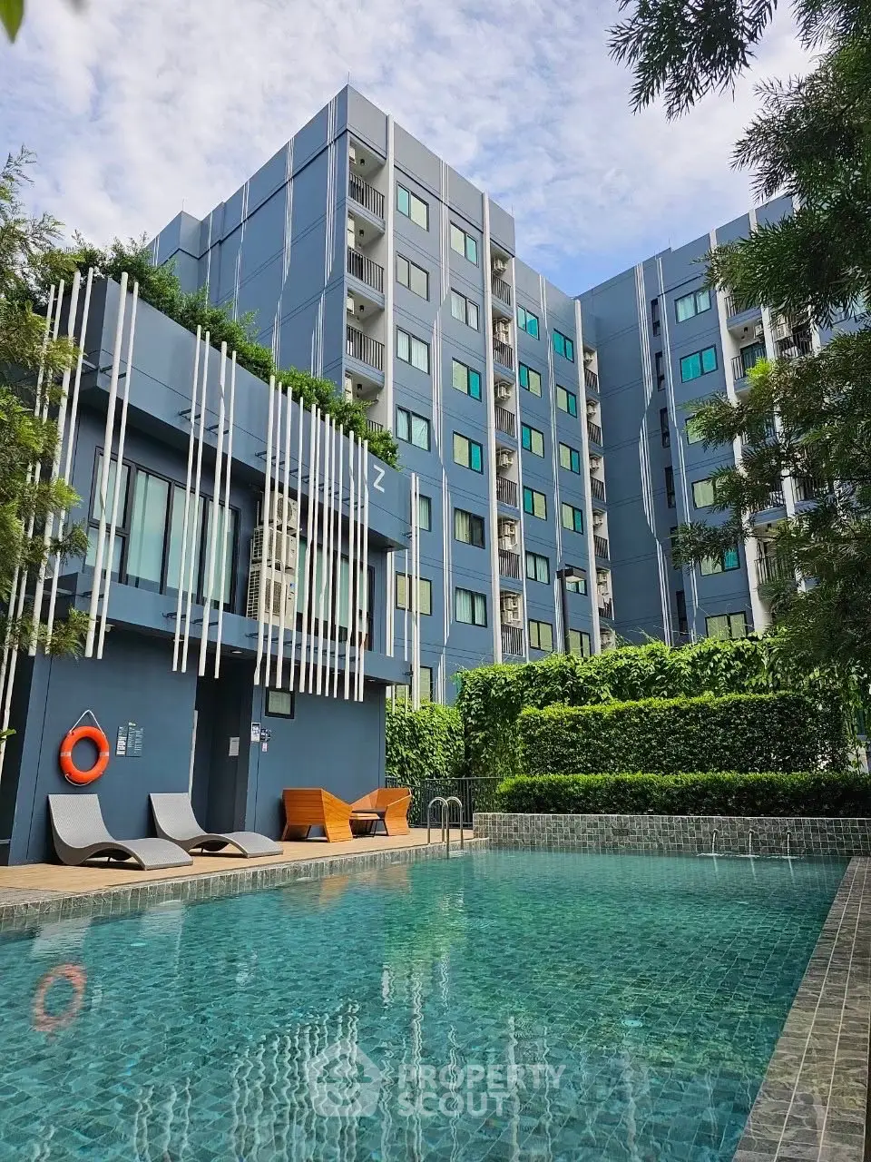 Modern apartment building with a luxurious swimming pool and lush greenery.