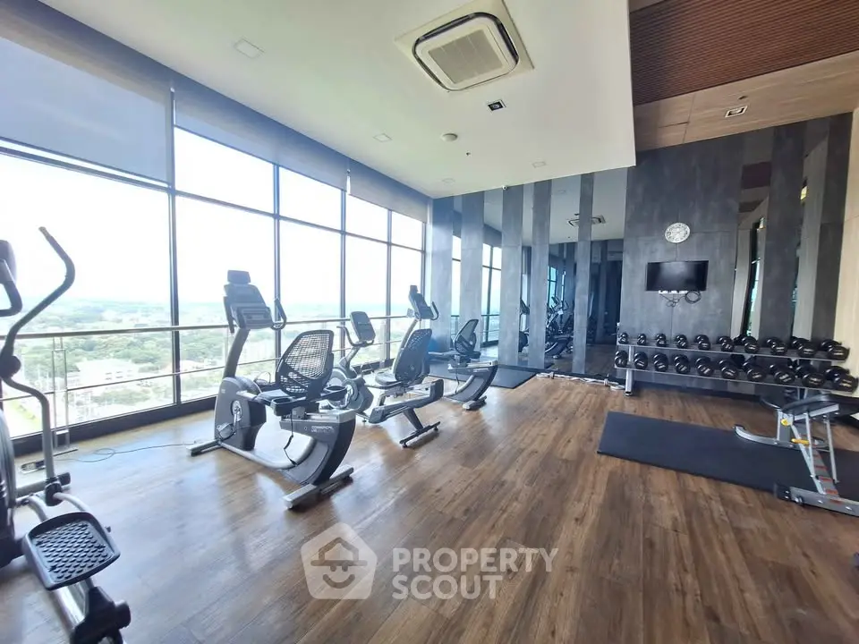 Spacious modern gym with panoramic windows and state-of-the-art equipment in luxury building.