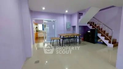 Spacious open-plan living area with modern staircase and dining setup.