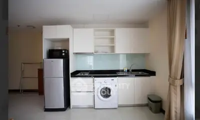 Modern kitchen with sleek cabinets, washing machine, and fridge in a compact layout.