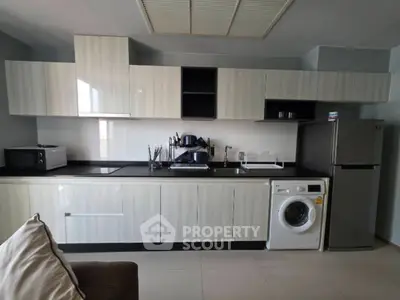 Modern kitchen with sleek cabinetry, washing machine, and stainless steel appliances.