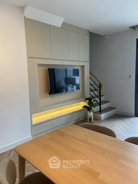 Modern living room with sleek TV setup and stylish staircase