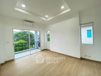 Spacious empty room with wooden flooring and balcony view