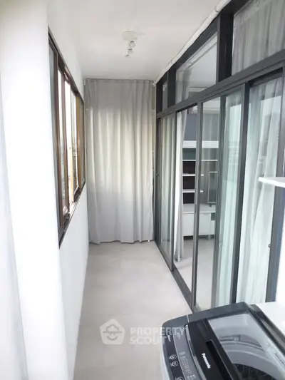 Bright enclosed balcony with sliding glass doors and washing machine