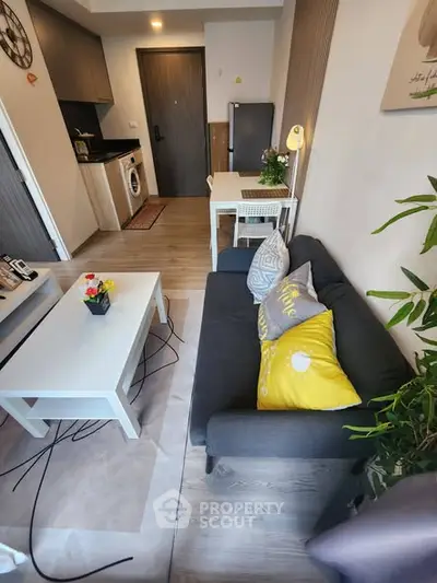 Modern living room with cozy seating and stylish decor in a compact apartment.