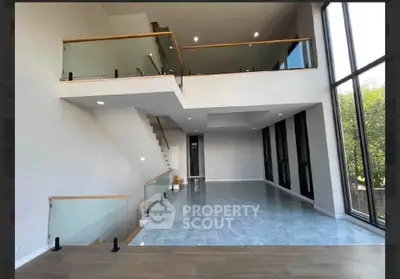 Spacious modern living room with high ceilings and large windows offering natural light.