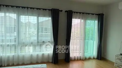 Spacious bedroom with large windows and elegant curtains offering a serene view of the neighborhood.