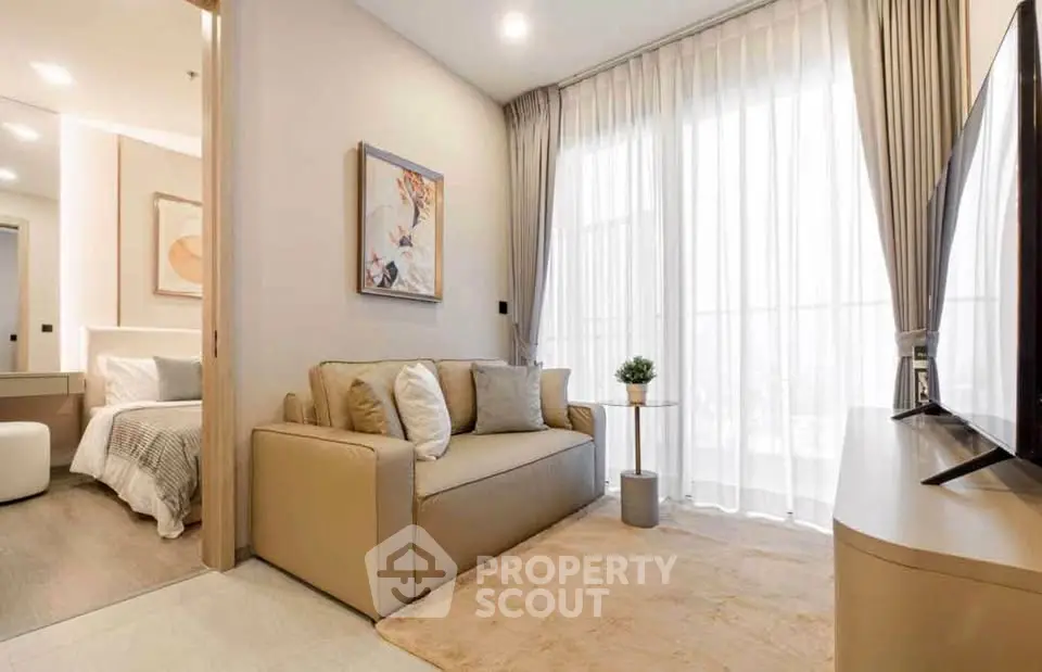 Modern living room with cozy sofa, large TV, and natural light from floor-to-ceiling windows.