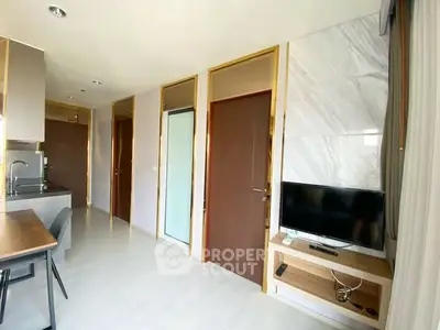 Modern apartment interior with sleek kitchen and cozy living area featuring a wall-mounted TV.