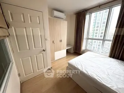 Bright and cozy bedroom with large window and modern furnishings in a high-rise apartment.