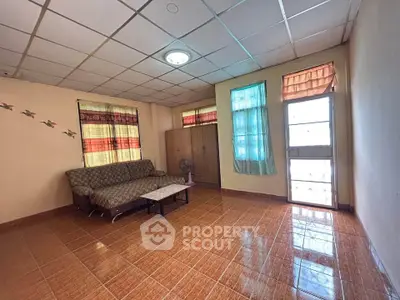 Spacious living room with tiled floor and cozy sofa, perfect for relaxation.