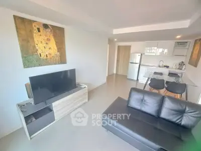 Modern living room with sleek furniture and open kitchen layout, featuring a stylish black sofa and wall art.