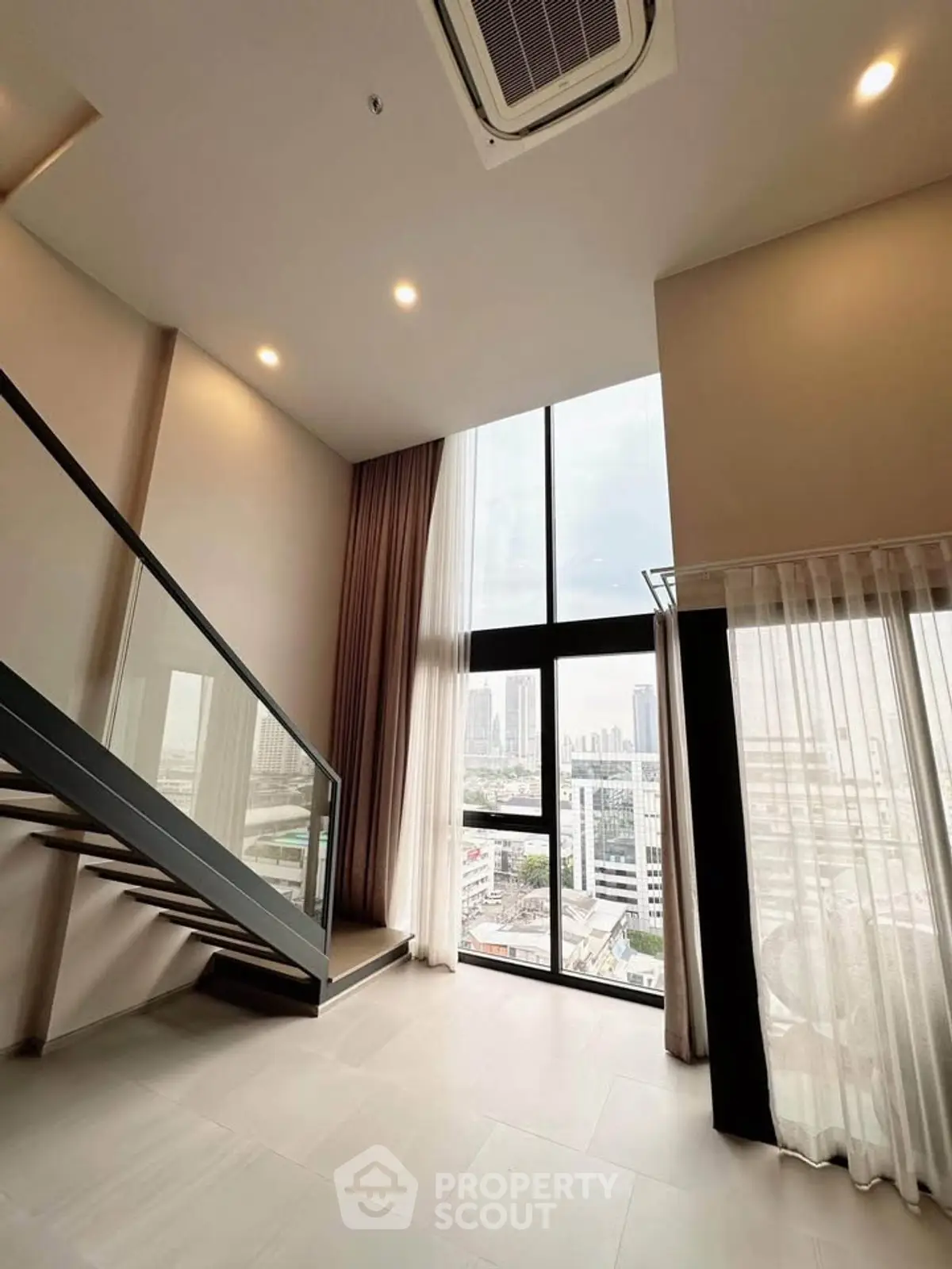 Spacious modern living room with high ceilings and large windows offering stunning city views.