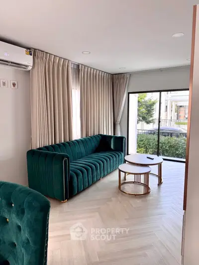 Modern living room with elegant green velvet sofa and chic coffee table, featuring large windows and stylish curtains.