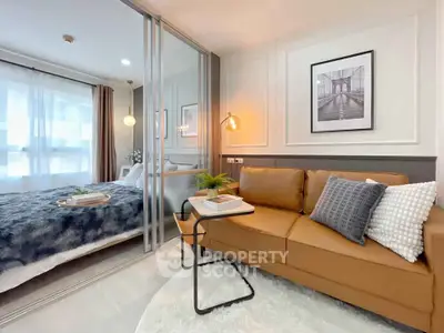 Modern living room with cozy sofa and stylish decor adjacent to a bedroom with glass partition.