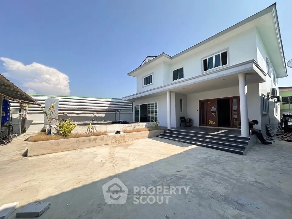 Modern two-story house with spacious concrete yard and clear blue sky.