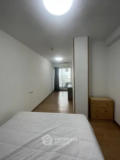 Spacious bedroom with wooden flooring and balcony access in modern apartment