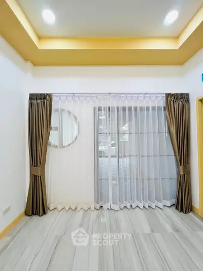 Elegant living room with modern ceiling lights and floor-to-ceiling windows with luxurious curtains.