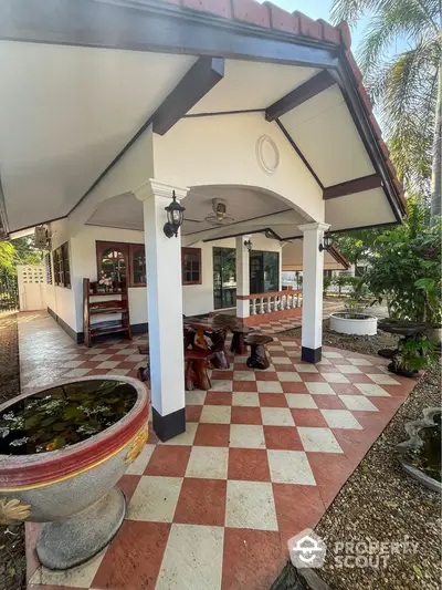 Charming exterior view of a spacious home with tiled patio and lush garden surroundings.